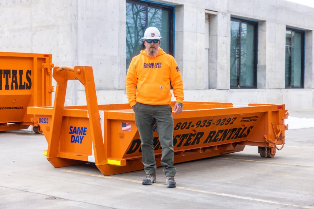 A man standing in front of a 7 yard dumpster provided by Sameday Dumpster