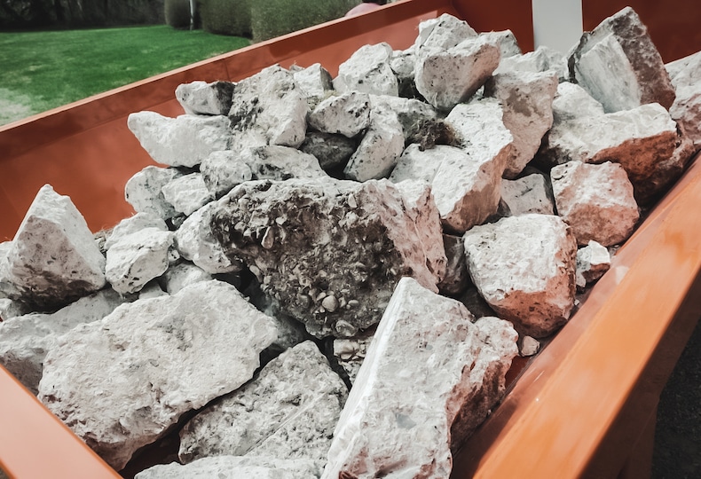 A yard full of rocks with a wheelbarrow full of rocks.