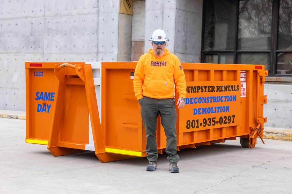 A man standing in front of a 12 yard dumpster provided by Sameday Dumpster